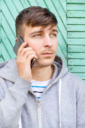 Sad Young Man call on the Phone on the Old Wall Background outdoorの写真素材