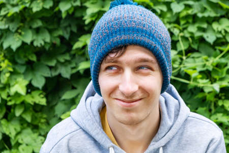 Young Man Portrait on the Green Leaves Background on the Streetの写真素材