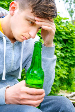Sad Young Man hold a Beer Bottle outdoor closeupの写真素材