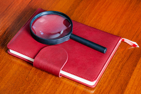 Red Book with a Magnifying Glass on the Wooden Table closeupの写真素材