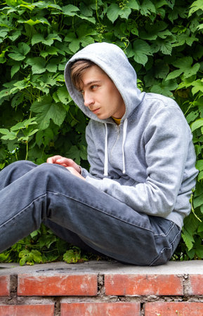 Sad Young Man on the Green Leaves Background outdoorの写真素材