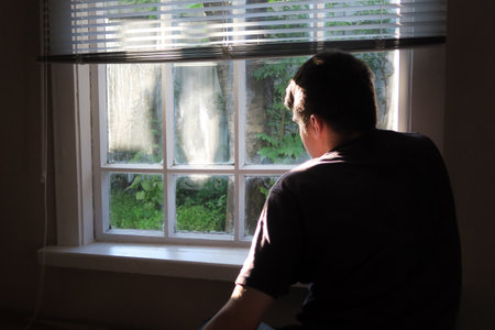Sad and Lonely Young Man sit near the Window at the Home