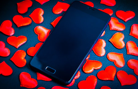 Mobile Phone on the Scattered Red Hearts Background closeupの写真素材