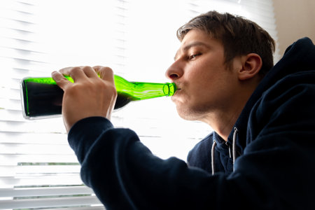 Young Man with a Beer by the Window in the Roomの写真素材