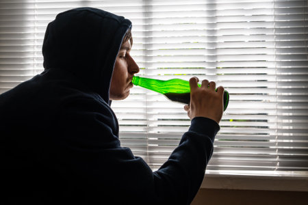 Young Man with a Beer by the Window in the Roomの写真素材