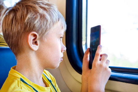 Kid take a Photo on the Phone by the Window in the Trainの写真素材