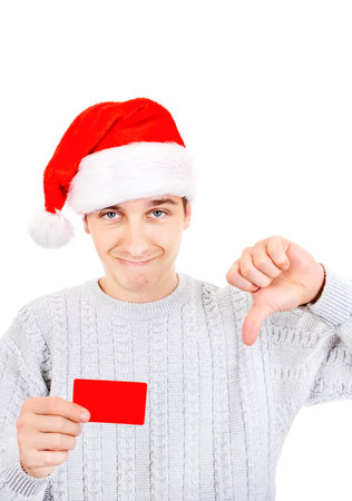 Unhappy Young Man in Santa Hat hold a Bank Card and make Thumb Down Gesture on the White Backgroundの写真素材