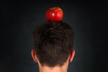 Rear View of the Man with an Apple on the Head on the Dark Background closeupの写真素材