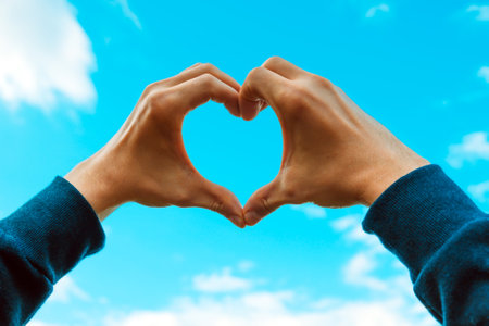 Hands in Heart Shape on Sky Background closeupの写真素材