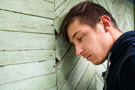 Sad Young Man by the Wall outdoorの写真素材