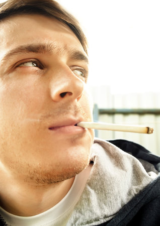 Young Man smoke a Cigarette. Portrait outdoor closeupの写真素材