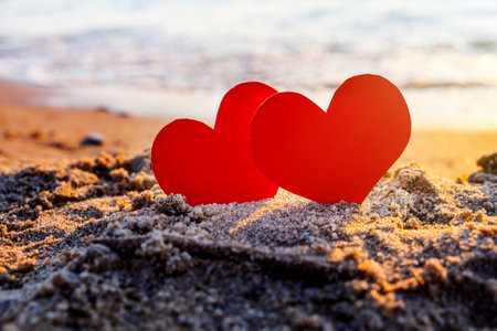Two Red Hearts in the Sand at the Evening Beachの写真素材