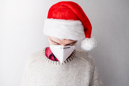 Sad Young Man Portrait in Santa Hat by the Wall in the Roomの写真素材
