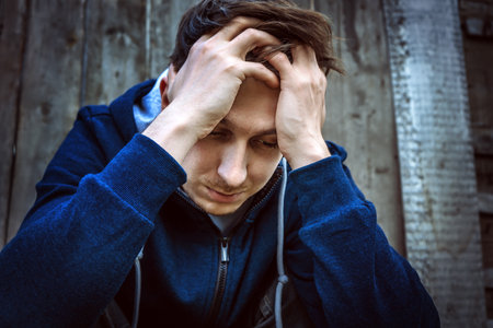 Sad Young Man on the Old Wooden Wall Background outdoorの写真素材