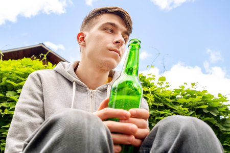 Unhappy Young Man hold a Beer Bottle outdoorの写真素材