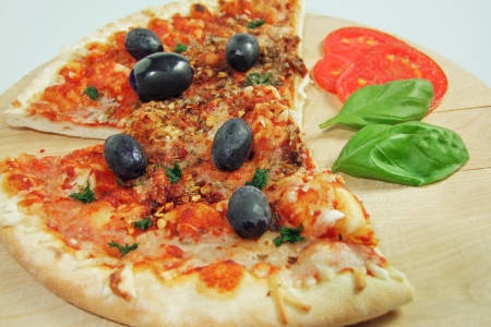 Pizza with Tomatoes, Black Olives and Basil on a cutting board, close upの写真素材