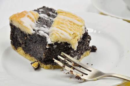 A Piece of Poppy Seed Cake, missing Bite, on white Plate with silver Fork, close upの写真素材