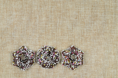 close up of three Christmas cookies with chocolate and hundreds and thousands, star shaped, on canvas with copy space, horizontalの写真素材