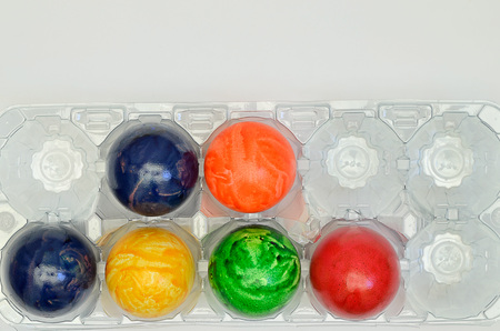 colorful Easter eggs in a plastic box, close up on white background, horizontalの写真素材