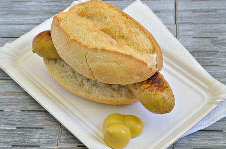 Sausage roll with mustard on white paper plate, close up, macro, full frameの写真素材