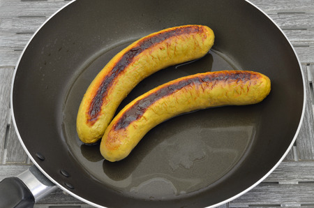 Two grilled sausages in a frying pan, close up, macro, full frameの写真素材