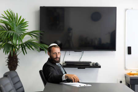 Businessman in a conference, meeting room. Jewish man in a yarmulke and glasses working at the...