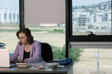 Woman thinking about something in Office, working using laptop reading email from client. Dollars,...