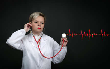 Studio photo of a Caucasian American Medical Professional In Lab Coat With Stethoscope. Confident female doctor posing on black background. Confident senior female cardiologist. Portrait Of Doctorの写真素材
