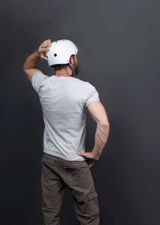 Back View of American handsome bearded man in a bicycle helmet. Russian Man after intense biking training. Active person looking forward and holding his hand behind a head, posing holding his helmetの写真素材