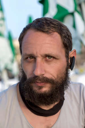 American handsome bearded man in wireless earpiece. concept Convenience of wireless headphones. Thoughtful Serious Russian man looking at camera using a hands free device to speak on the phoneの写真素材
