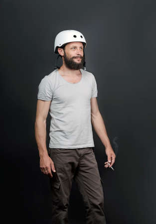 American handsome bearded man in a bicycle helmet. safety device for protect health. Serious Russian Man Smoking Cigarette. Sport and harmful habit. Smoking causes lung cancer and other diseases.の写真素材
