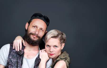 Portrait of american couple hugging in studio. handsome man beard wearing a cap, sunglasses, hoody vest and Russian woman blonde hair giving a warm hug to her husband in expression of her. Copy spaceの写真素材