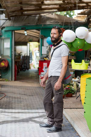 handsome American Caucasian bearded man wearing sunglasses in buying pot at garden center. Russian buyer chooses the plants to buy in flower shop. Happy gardener in a greenhouse choosing a flower potsの写真素材