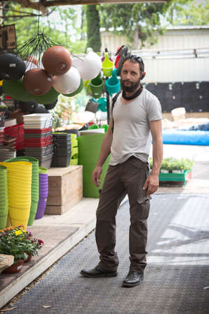 handsome American Caucasian bearded man wearing sunglasses in buying pot at garden center. Russian buyer chooses the plants to buy in flower shop. Happy gardener in a greenhouse choosing a flower potsの写真素材
