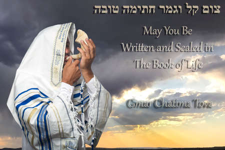 Hebrew inscription gmar chatima tova next to Jewish man wrapped in tallit, prayer shawl with the inscription "Baruch Atah Adonai" written on it in Hebrew, holding the Shofar, ram's horn of Yom Kippurの写真素材