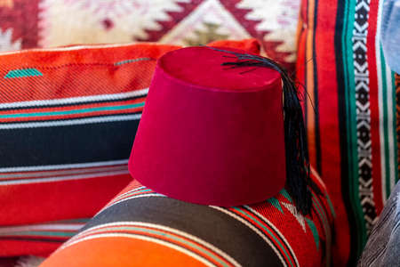 Fez or tarboosh with arabic or Ottoman style on Turkish Fabric Pattern. Oriental islamic middle eastern decor and Clothing, selective focus. Red turkish hat in classical oriental design home. colorfulの写真素材