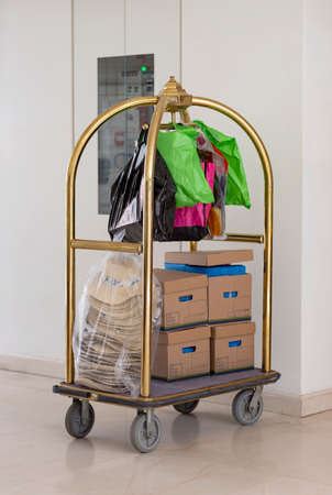 Luggage trolley cart packed with lots of things ready for the road trip. Many packages on hotel luggage cart. Trolley luggage at the hotel with a boxes stacked one above the other for transport.の写真素材