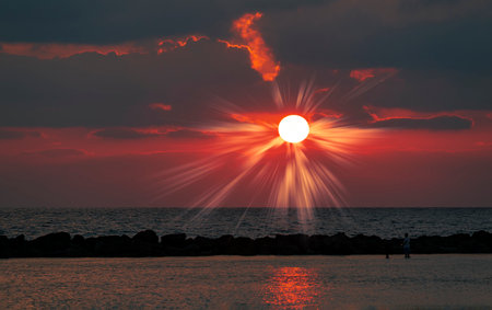 Red sky sunset in the sea with red clouds background. travel concept. Landscape amazing of bright orange-red dark sky and light of the sun. seascape background. Colorful sunset sky at a beachの写真素材
