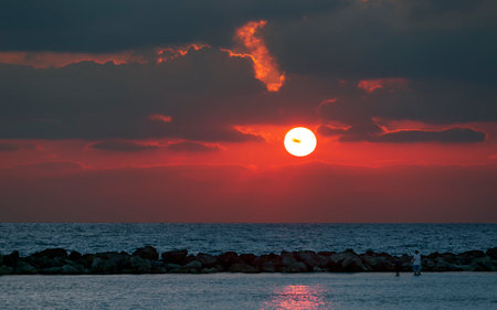 Sunset over the sea with beautiful dark dramatic blazing sky. seascape in the evening. Amazing red sunset sky at a beach. Evening purple sunset sky on the shores with fluffy clouds. fantasy landscapeの写真素材