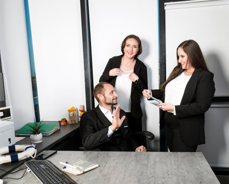 Caucasian woman giving bribe dollars in office. A woman in a black suit gives a stack of money to a man's hand, which refuses. Businesswoman with long hair holding money in hands. Two women smilingの写真素材