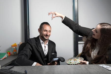 Playful woman giving, offering candy to jewish businessman in office. Israeli woman with a beautiful...