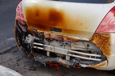 Rear view of burned out car on roadside down in the middle of the street. Burnt new car of a bumper, vandalism, mafia. Setting fire to cars of a terrorist attack in the city. Accident on the roadの写真素材