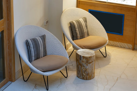 Living room interior design with two wicker chairs. Set of wicker rattan furniture for the garden or terrace. Two armchairs with soft pillows and a coffee table. Living room with outdoor furniture.の写真素材
