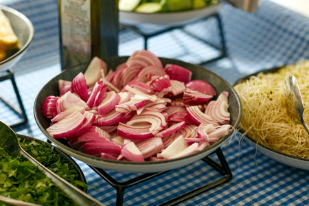 Soft selective focus of red onion chopping, farm organic vegetables on a cooking table. Vegetarian healthy food. A plate with chopped red onions for cooking on a dish. Red onions on wooden board.の写真素材