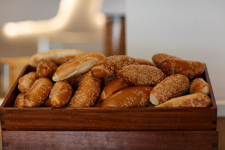 Buns white sesame seeds in wooden tray. Freshly baked whole grain bread with bran, seeds. Healthy multi-grain baked goods, close up. soft focus. Group crisp fresh homemade bread roll or bun with flaxの写真素材