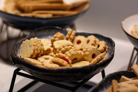 Jelly cookies flower with red jam homemade on a dark plate on a defocused background background....