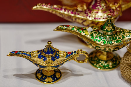 Aladdin's mysterious lamp. Precious golden magic lamp on blurred background, fairy tales and wish fulfillment concept. Background with selective focus and copy space. Close up of gold decorative lampsの写真素材
