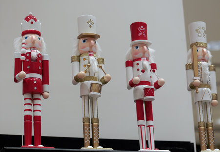 Line of nutcracker soldiers in red white uniform. Wooden Christmas figurines on the shelf. Santa nutcrackers on white background. Set of figure wooden nutcrackers, doll on the shelf in store with toysの写真素材