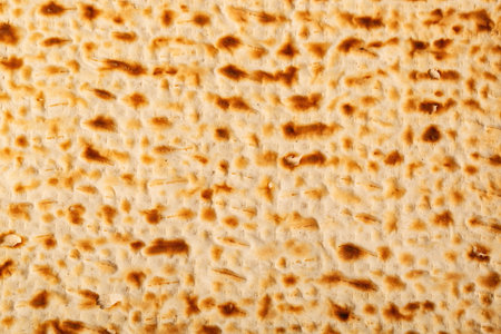 Close up view of matzah, an unleavened flatbread significant in Jewish Passover. The surface is perforated and browned, highlighting its baked texture. Passover matzo, Jewish unleavened matzo bread.の写真素材