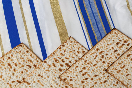 Matzah, a traditional unleavened bread, on a Tallit, a Jewish prayer shawl with stripes in different shades of blue, white, and gold. This scene is associated with the Jewish holiday of Passoverの写真素材
